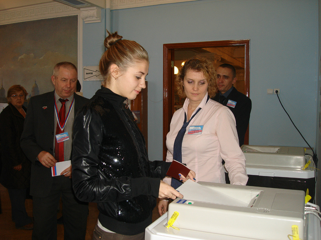 Первое голосование юной избирательницы через комплекс обработки избирательных бюллетеней (КОИБ) на избирательном участке № 2253. 14 октября 2012 года. (Архив Тагилстроевской территориальной избирательной комиссии)